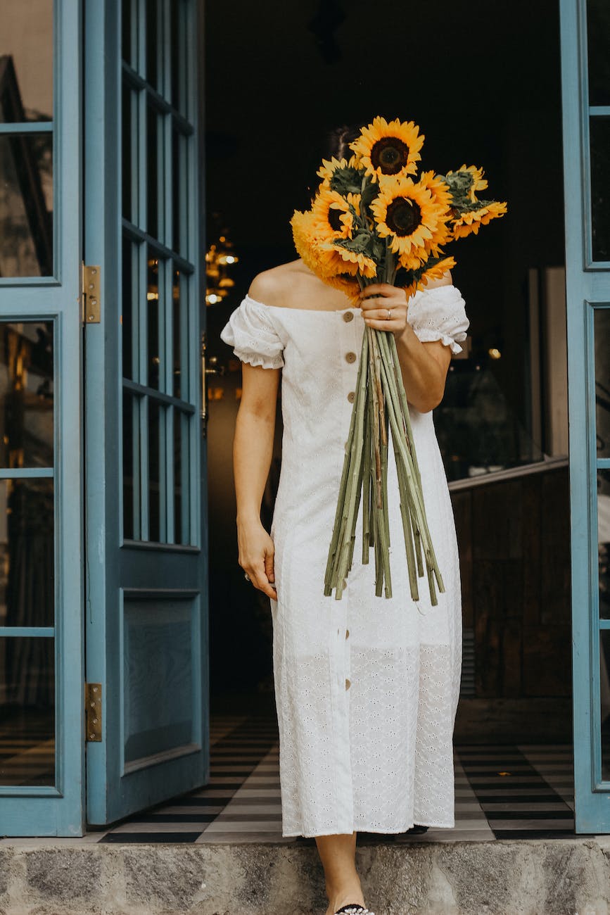 woman in dress posing with sunflowers