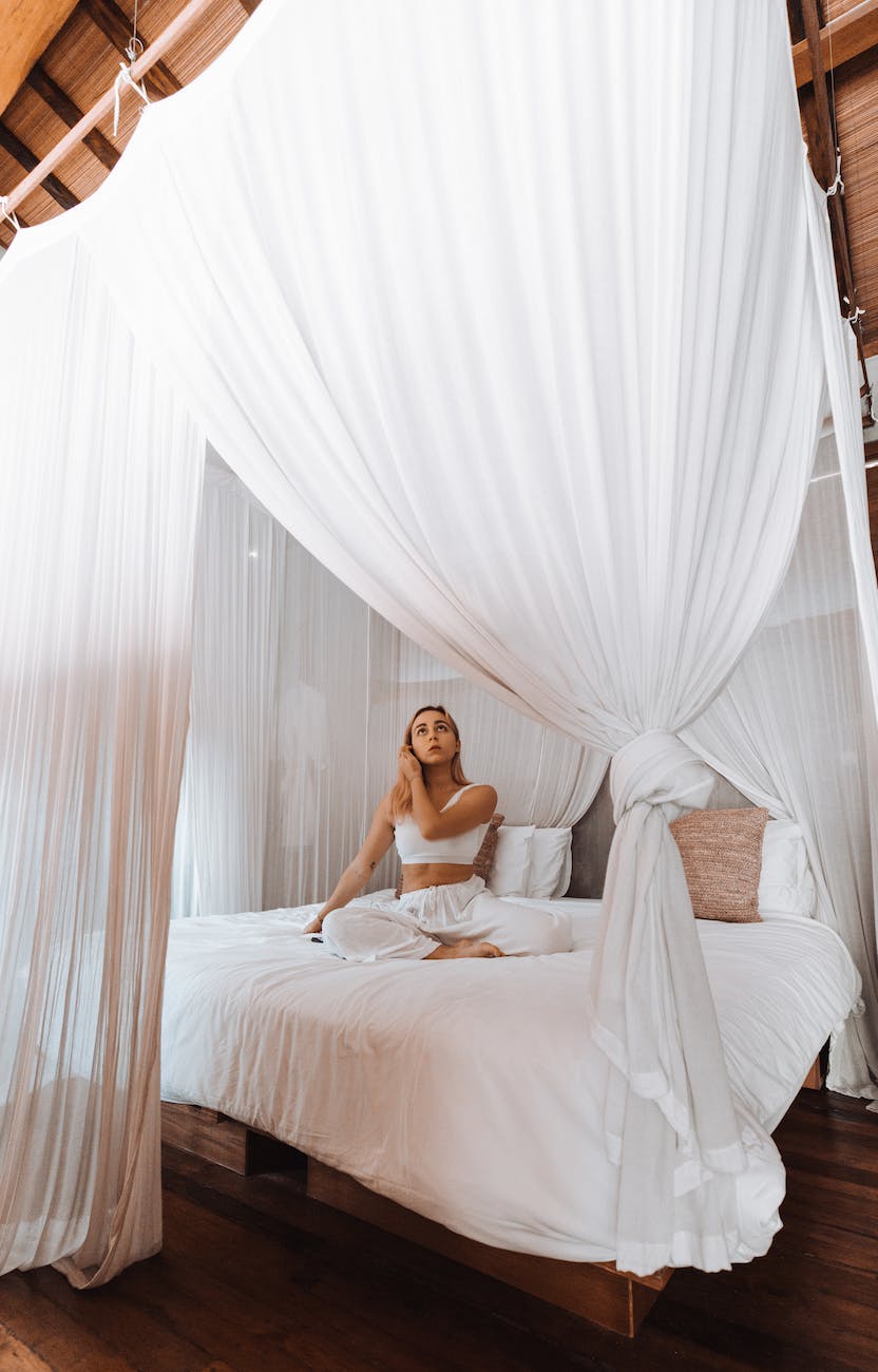 woman relaxing on canopy bed at home