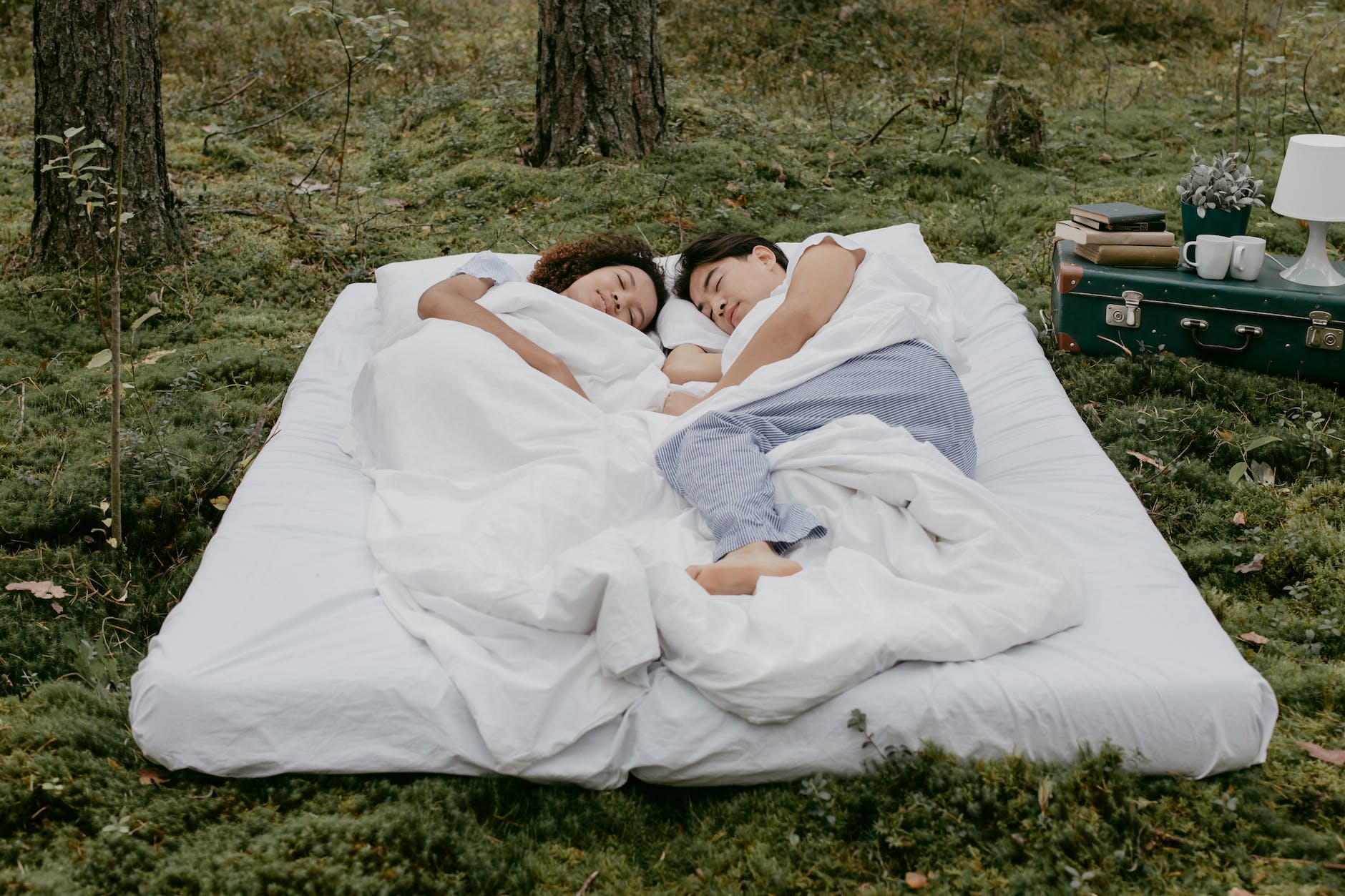 a couple lying down on a mattress outdoors