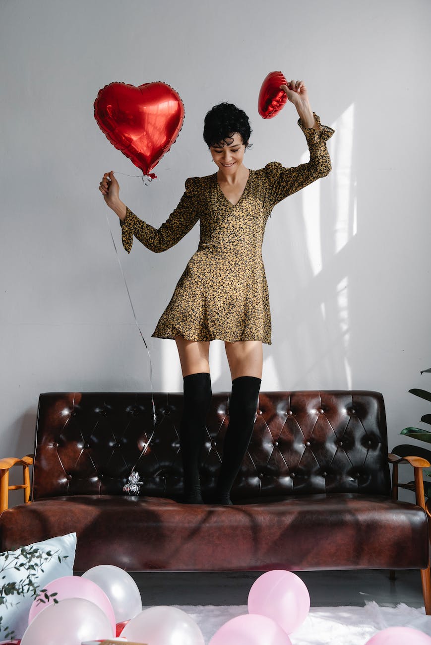 cheerful young woman in trendy dress with heart shaped balloons
