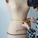 female designer measuring waist of mannequin