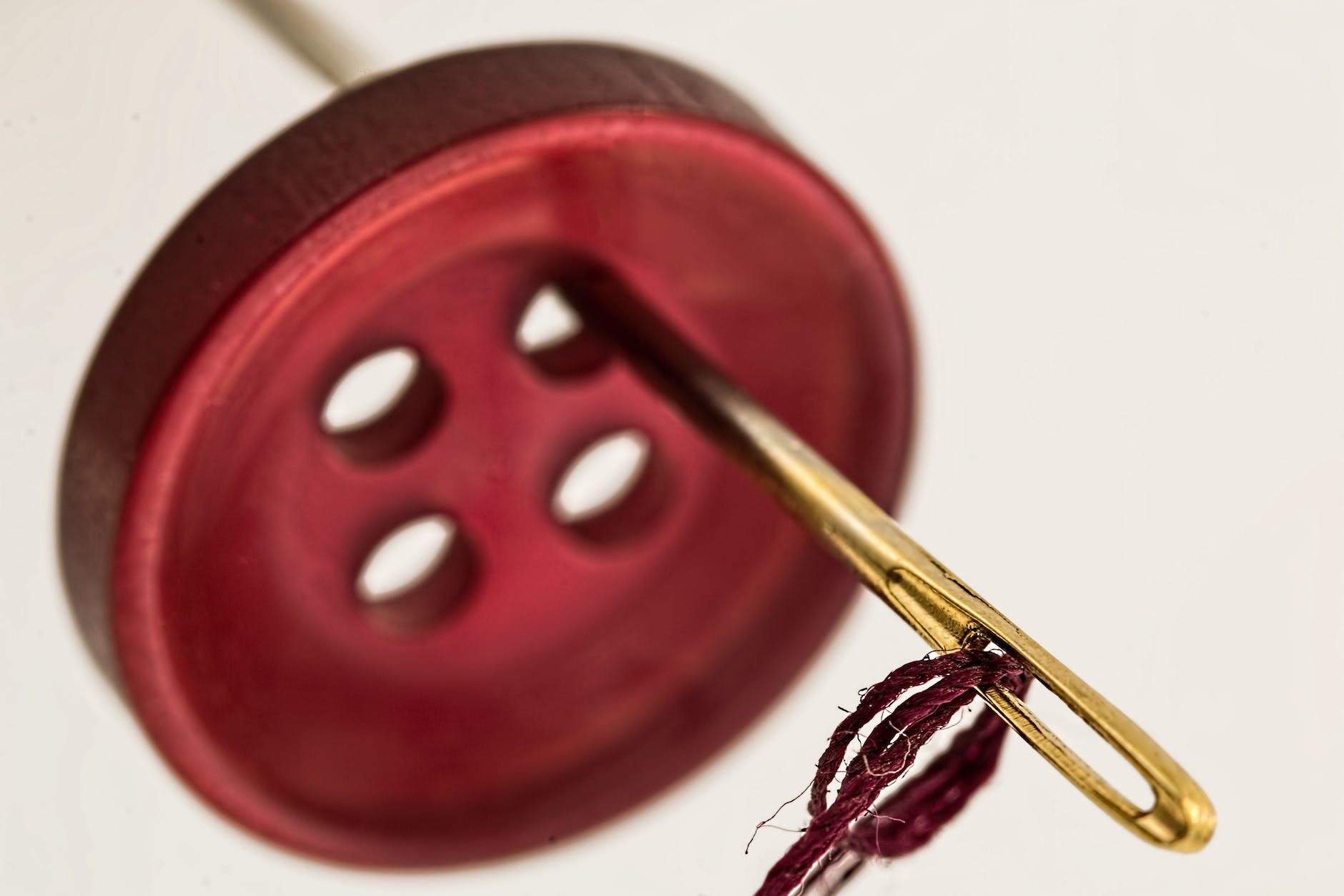 brass needle through red cloth button