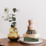 soaps with shaving brush near vase on wooden table