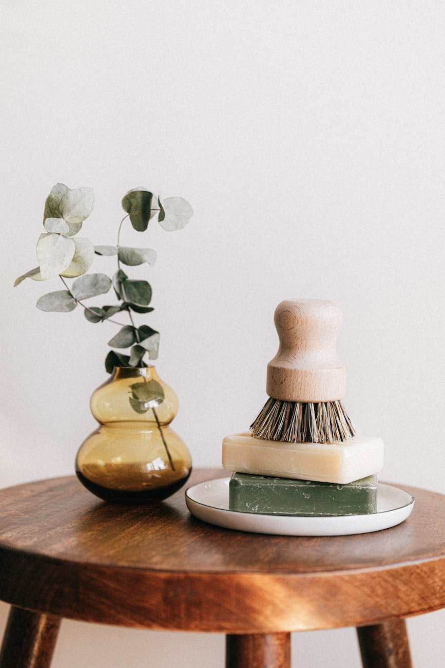 soaps with shaving brush near vase on wooden table