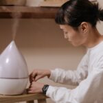 a woman in white sweater sitting beside the wooden table with humidifier