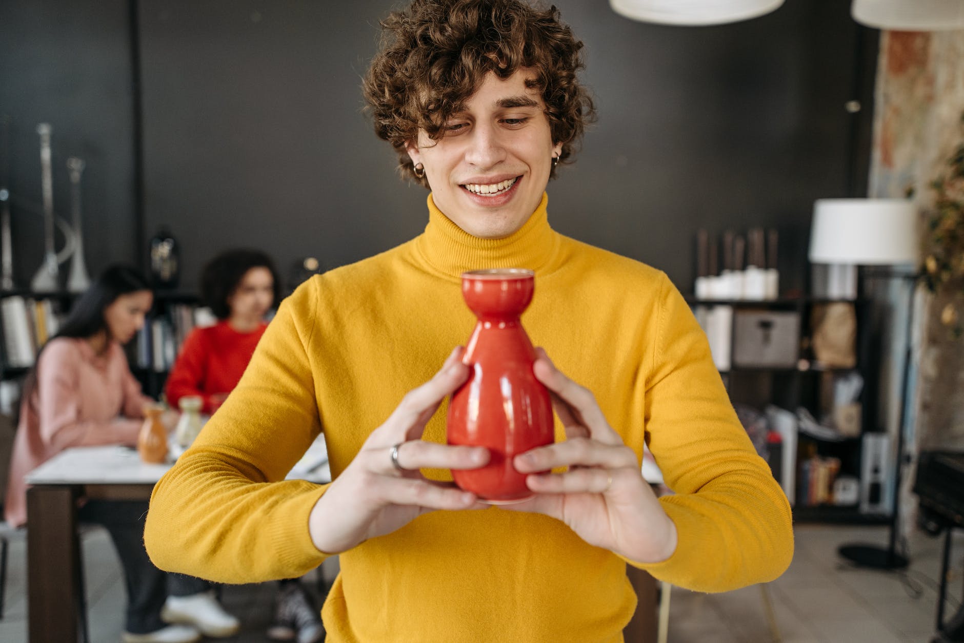 a man in yellow sweater holding ceramic object