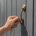 An image depicting a person holding a sturdy metal hook, placing it carefully in the top edge of a vinyl siding panel